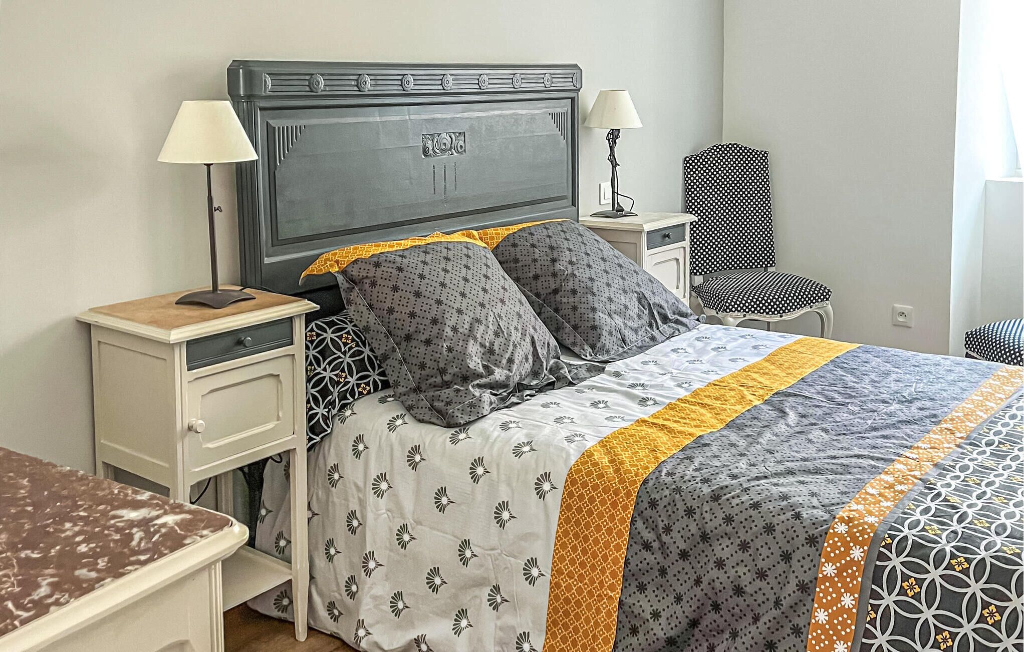 Une chambre bien rangée, avec un lit, deux tables de chevet, une chaise et une lampe.