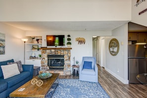 A living room with a stone fireplace, a blue sofa, a coffee table, and a blue armchair.