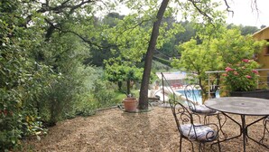A patio area with a table and chairs, surrounded by gravel and greenery. - Villa Capucine (Flayosc)