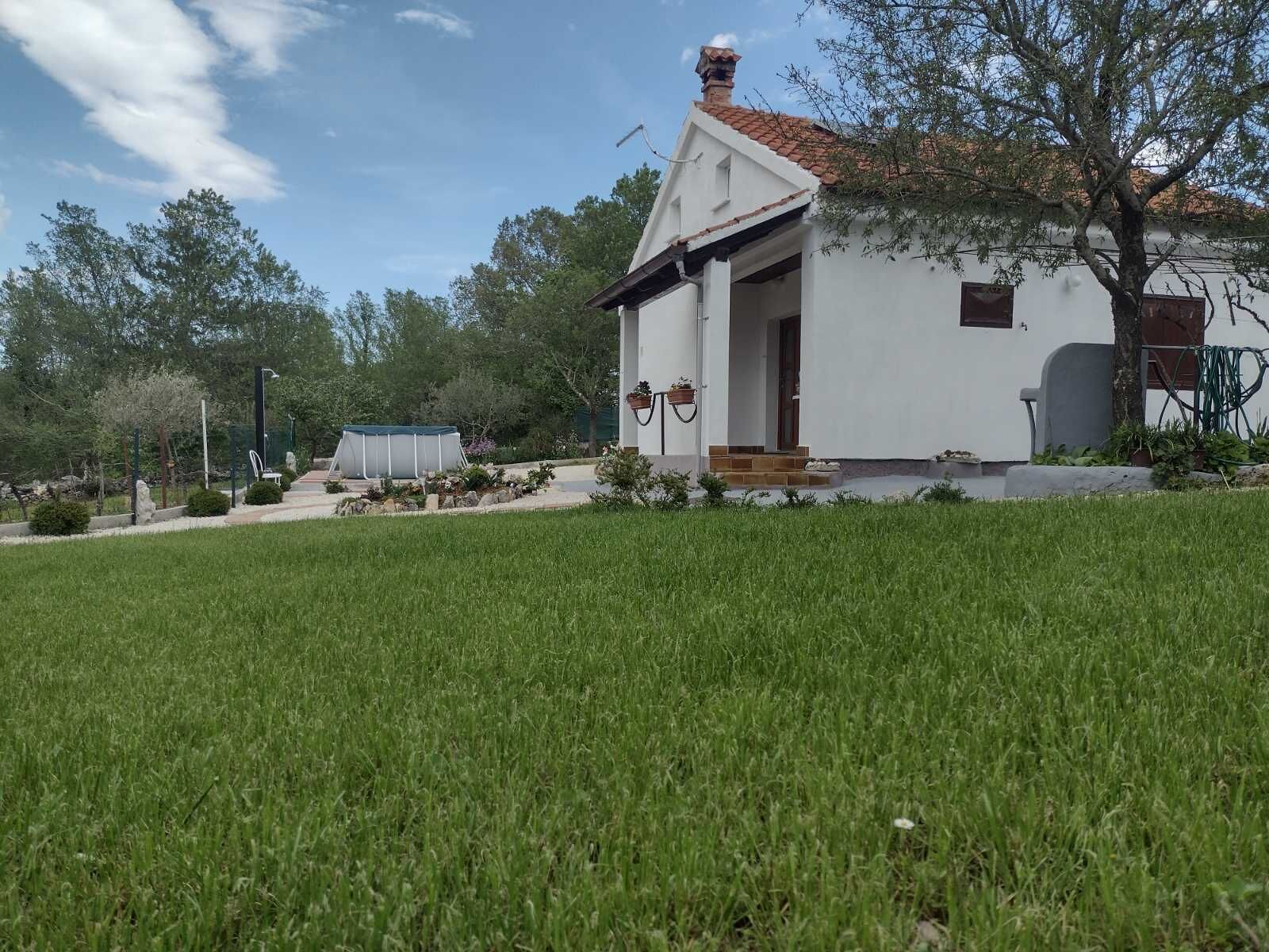 A white house with a tiled roof, a covered porch, and a well-maintained lawn.