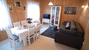 A cozy living room with a grey sofa, a dining table with chairs, a TV, and a cabinet with glass doors. - Vacation home near Rovinj quiet location with large garden, terrace, WLAN (Mrgani)