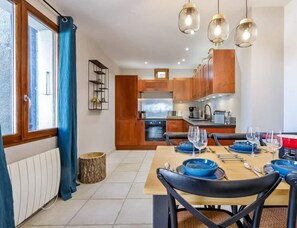 Una cocina moderna con armarios de madera, una mesa de comedor preparada para seis personas e iluminación colgante.