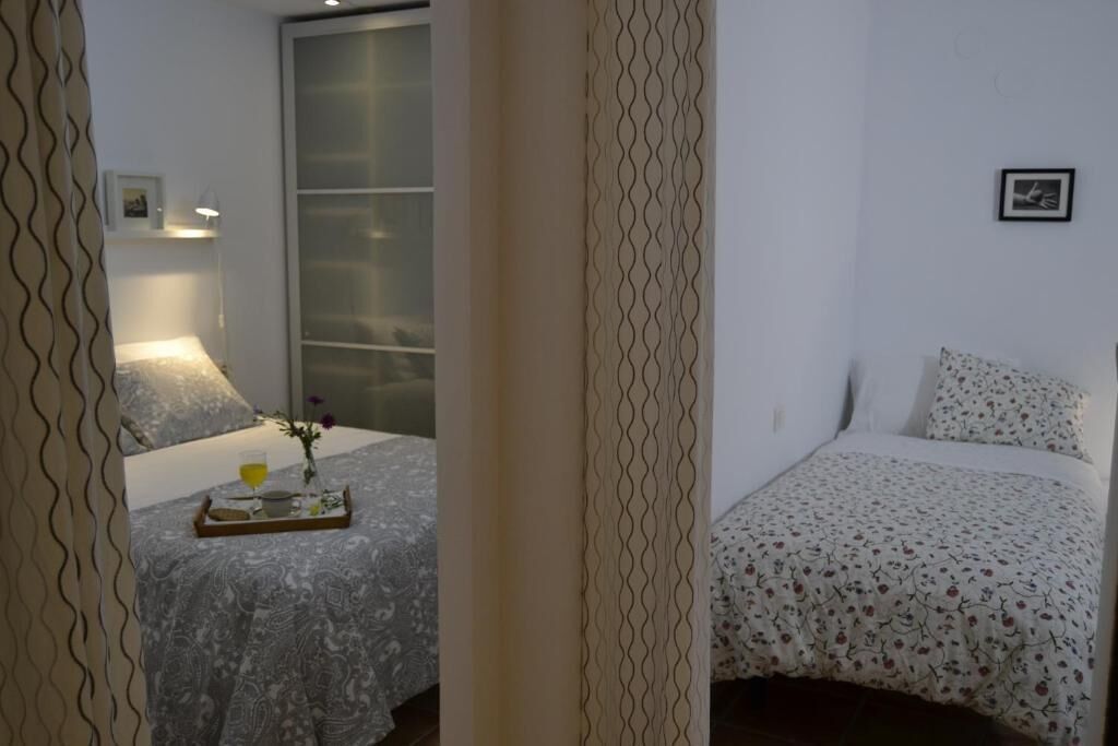 A bedroom with a bed, a bedside table with a lamp, and a window.