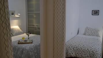 A bedroom with a bed, a bedside table with a lamp, and a window.