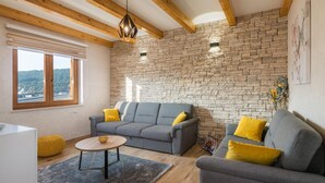 Una sala de estar moderna con pared de piedra, vigas de madera y vista a un puente.
