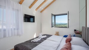 Un dormitorio con cama, ventana con vistas, televisor de pantalla plana y un osito de peluche.