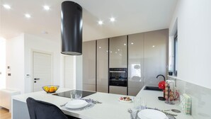 Una cocina moderna con una isla central, horno empotrado y una campana extractora negra.