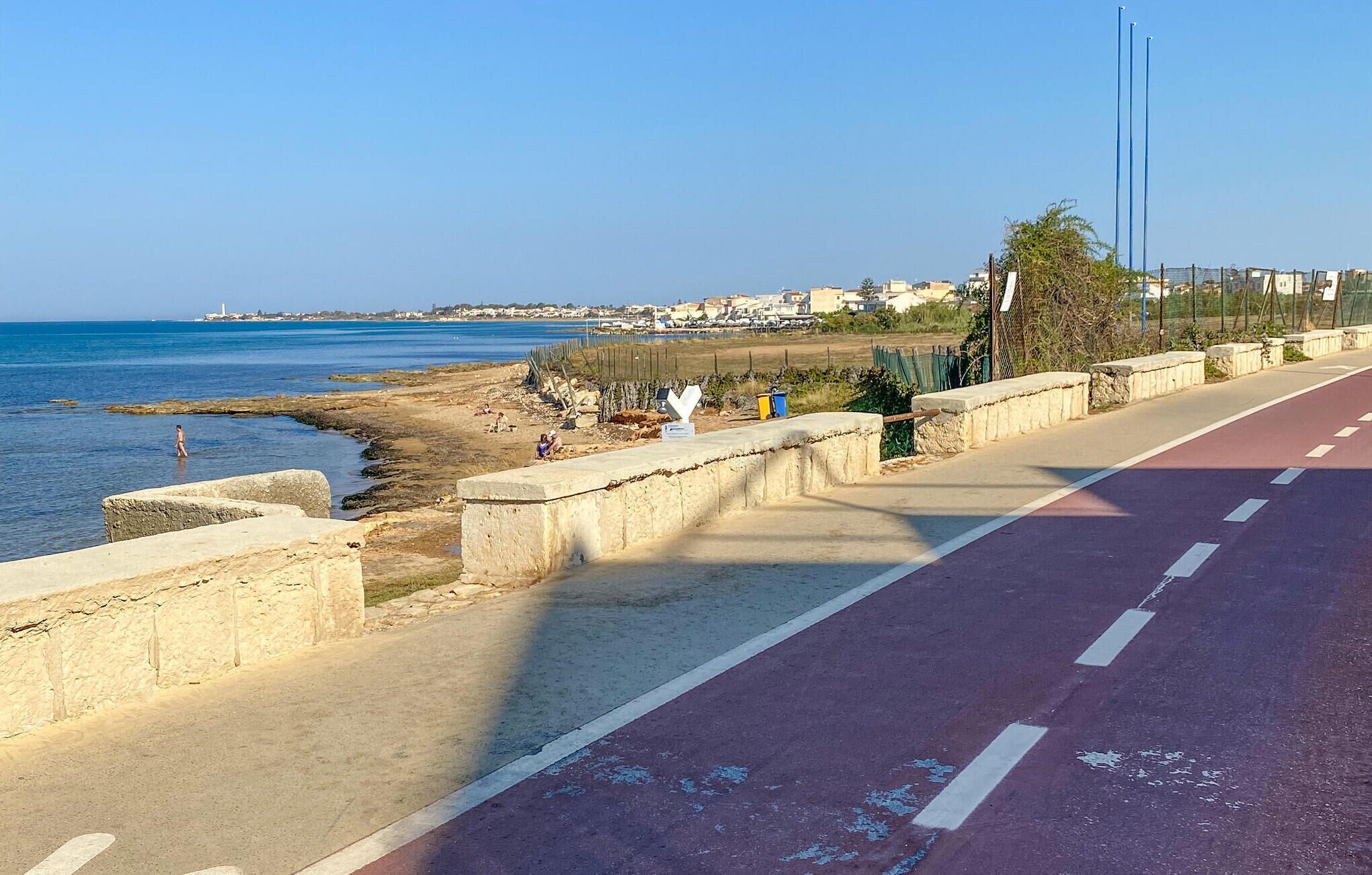 A coastal road with a pedestrian walkway alongside a beach.