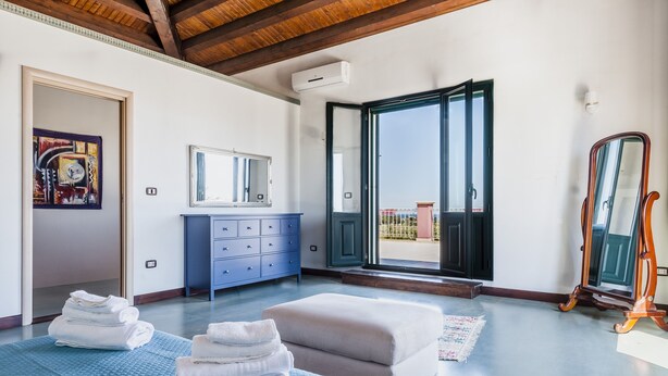 A bedroom with a bed, a dresser, a mirror, and a view of the outside. - Charming Sea View Villa close to beach (Syracuse)