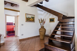 Stunning interior space with a grand staircase, woven basket vase, and framed artworks.