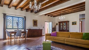 A spacious living room with a wooden ceiling, a yellow sofa, a green ottoman, and a patterned rug. - Charming Sea View Villa close to beach (Syracuse)