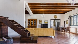 A spacious living room with a wooden staircase, a yellow sofa, a dining area, and a large window. - Charming Sea View Villa close to beach (Syracuse)