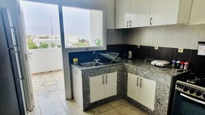 Eine Küche mit Granit-Arbeitsplatten, weißen Schränken, einem Einbauofen und Blick durch das Fenster.