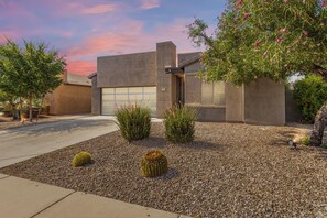 A modern two-story house with a garage, landscaped with gravel and small plants.