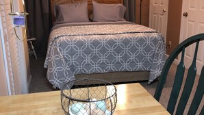 Ein Hotelzimmer mit einem Bett, einem Tisch, einem Stuhl, einem Deckenventilator und einer Lampe.