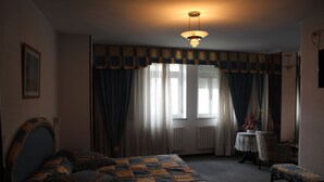 A bedroom with a bed, a chair, a table with a vase, and a window with curtains. - Hotel Santa Clara (Monforte de Lemos)
