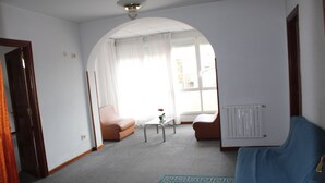 A living room with a blue sofa, a brown armchair, a coffee table, and a radiator. - Hotel Santa Clara (Monforte de Lemos)