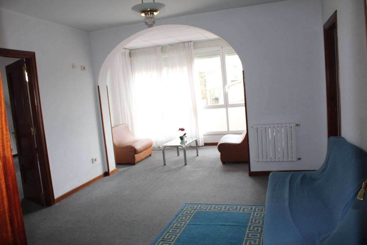 A living room with a blue sofa, a brown armchair, a coffee table, and a radiator.