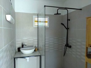Une salle de bain avec une douche à parois de verre, un lavabo blanc et un meuble en bois.