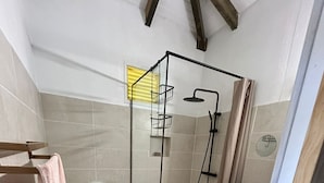 Et badeværelse med bruser, toilet og håndvask.