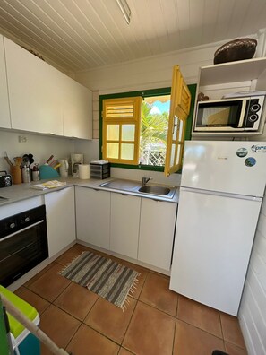 A compact kitchen with white cabinets, a built-in microwave, and a window with a view of greenery.