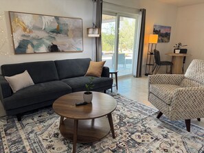 A living room with a sofa, armchair, coffee table, and a painting on the wall. - Peaceful Private Casita in the Catalina Foothills near Sabino Canyon (Tucson)