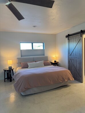A bedroom with a bed, two bedside lamps, a window, a ceiling fan, and a wooden door. - Peaceful Private Casita in the Catalina Foothills near Sabino Canyon (Tucson)