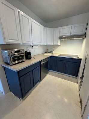 A kitchen with white cabinets, a stainless steel oven, a dishwasher, and a countertop with a coffee maker.