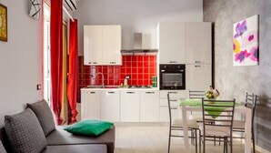 Eine moderne Küche mit weißen Schränken, einer roten Spritzschutzleiste und einem Essbereich mit Tisch und Stühlen.