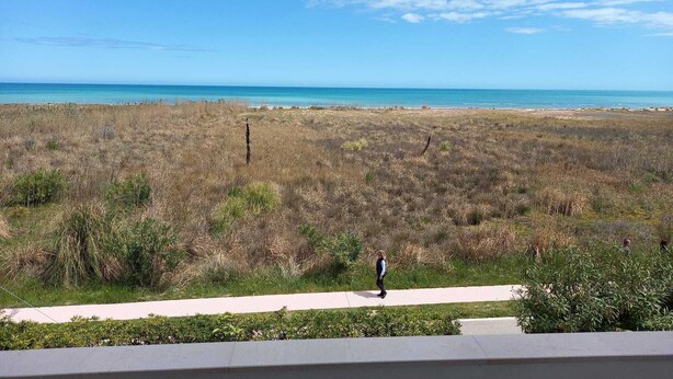A coastal landscape with a clear sky, a person walking on a path, and a view of the ocean. - Sea front apartment, fine sandy beach, trabocchi coast (Marina di Vasto)