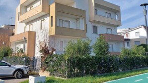 A modern multi-story residential building with balconies, a car parked in front, and a green bike lane. - Sea front apartment, fine sandy beach, trabocchi coast (Marina di Vasto)