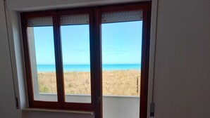 A room with a view of the beach through a door with glass panels. - Sea front apartment, fine sandy beach, trabocchi coast (Marina di Vasto)