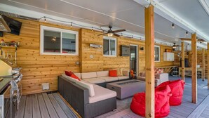 Eine Holzhütte mit einer Terrasse, einem Sofa, einer Feuerstelle und einem roten Sitzsack.