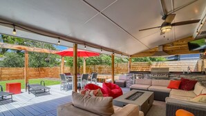 Eine Terrasse im Freien mit überdachter Sitzgruppe, Grill und Feuerstelle.