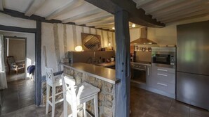 Una cocina con pared de piedra, barra de madera y refrigerador de acero inoxidable.