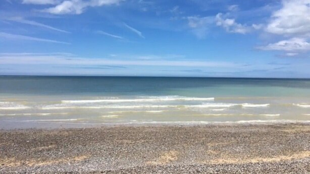 Una playa con piedras y un cielo azul despejado.