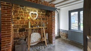 Una chimenea de ladrillo rústica con una decoración en forma de corazón, un candelabro y un pequeño estante con diversos objetos.