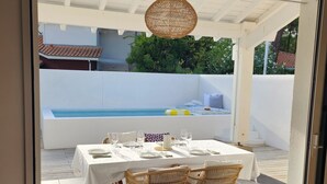 An outdoor dining area with a table set for two, wicker chairs, and a hanging light fixture. - Charming house in Biscarrosse Plage with heated swimming pool  (Nouvelle-Aquitaine)