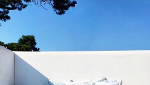 A pool with a yellow and white inflatable ring, a white wall with a built-in seating area, and a clear blue sky. - Charming house in Biscarrosse Plage with heated swimming pool  (Nouvelle-Aquitaine)