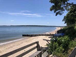Une plage avec une promenade en bois menant au rivage, une plage de sable et une vue sur la mer.