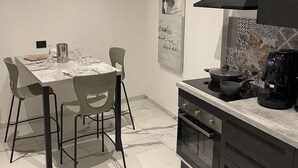 A modern kitchen with a marble countertop, a built-in oven, and a coffee machine. - Designer apartment in the historic center (Palermo)
