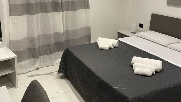 A modern hotel room with a large bed, a desk, and a chair. - Designer apartment in the historic center (Palermo)