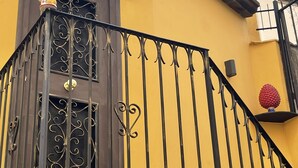 A yellow building with a stone staircase leading to a door with a decorative metal railing. - Designer apartment in the historic center (Palermo)