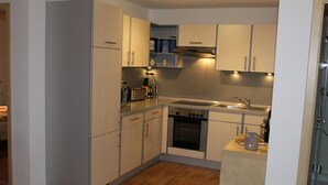 A compact kitchen with white cabinets, a built-in oven, a microwave, and a sink. - Small vacation apartment (65m²) with "beautiful view" Garden with playground (Nieder-Werbe)