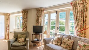 Ein Wohnzimmer mit einer Couch, einem Sessel und einem Fernseher.