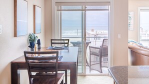 Un comedor con una mesa, sillas y vista al océano a través de un ventanal corredera.