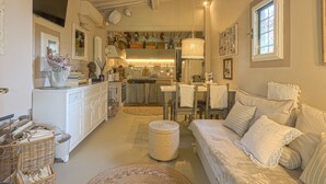 A cozy interior with a dining area, kitchen, and a comfortable seating area with a sofa and pillows.