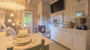 A cozy dining area with a fireplace, a television mounted on the wall, and a dining table set for two.