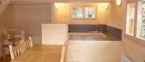 A wooden cabin with a dining area, a kitchenette, and a window.