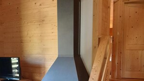 A modern log cabin interior with a wood-burning stove, a wooden staircase, and a television on a wooden cabinet. - Chalet, view mountain, terrace, tv, 85m², Villard de Lans (Lans-en-Vercors)